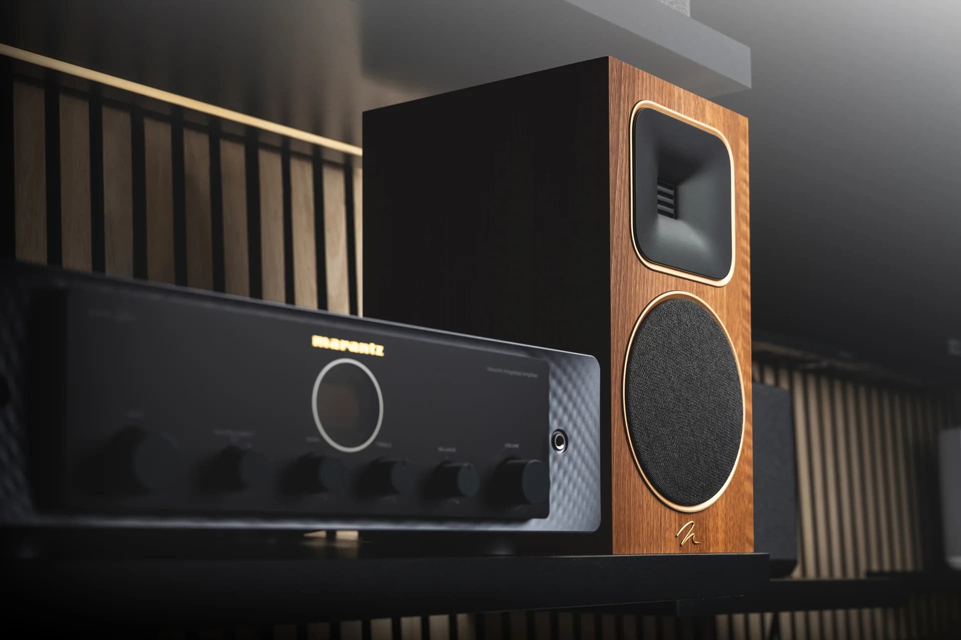 A Marantz amplifier beside a walnut bookshelf speaker